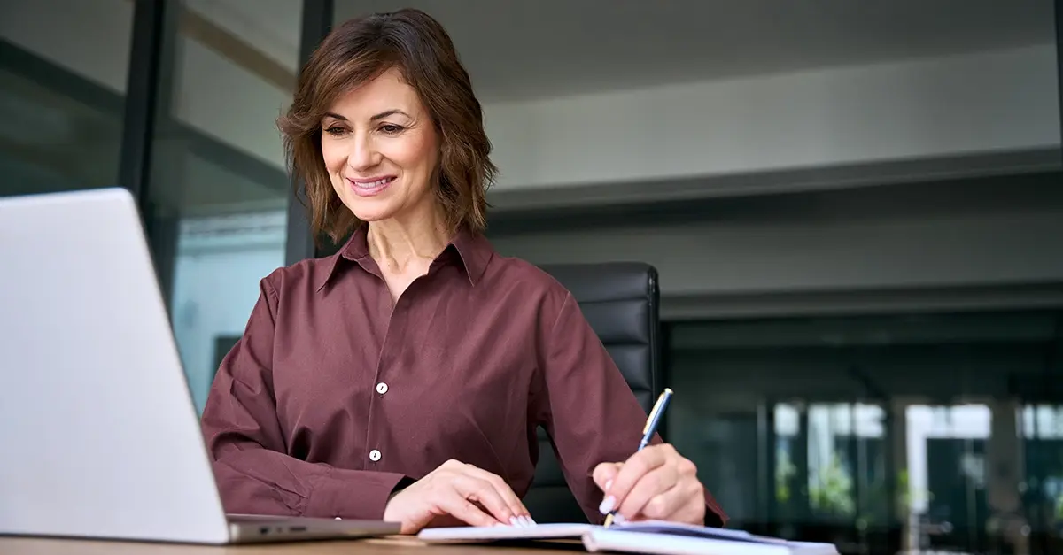A compliance officer at a laptop reviewing training records in a small firm office