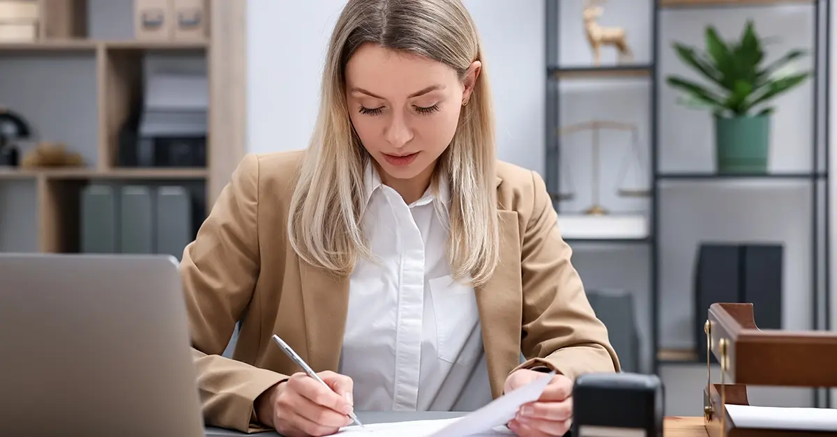 A compliance officer at a laptop reviewing training records in a small firm office