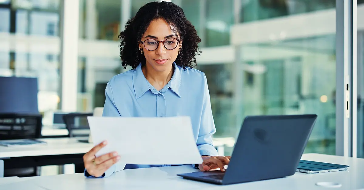 A compliance officer at a laptop reviewing training records in a small firm office